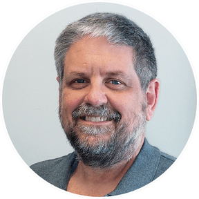 A photo of a white man with a grey beard and hair.